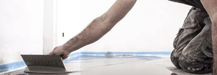 Person verteilt Estrich mit Glätter.